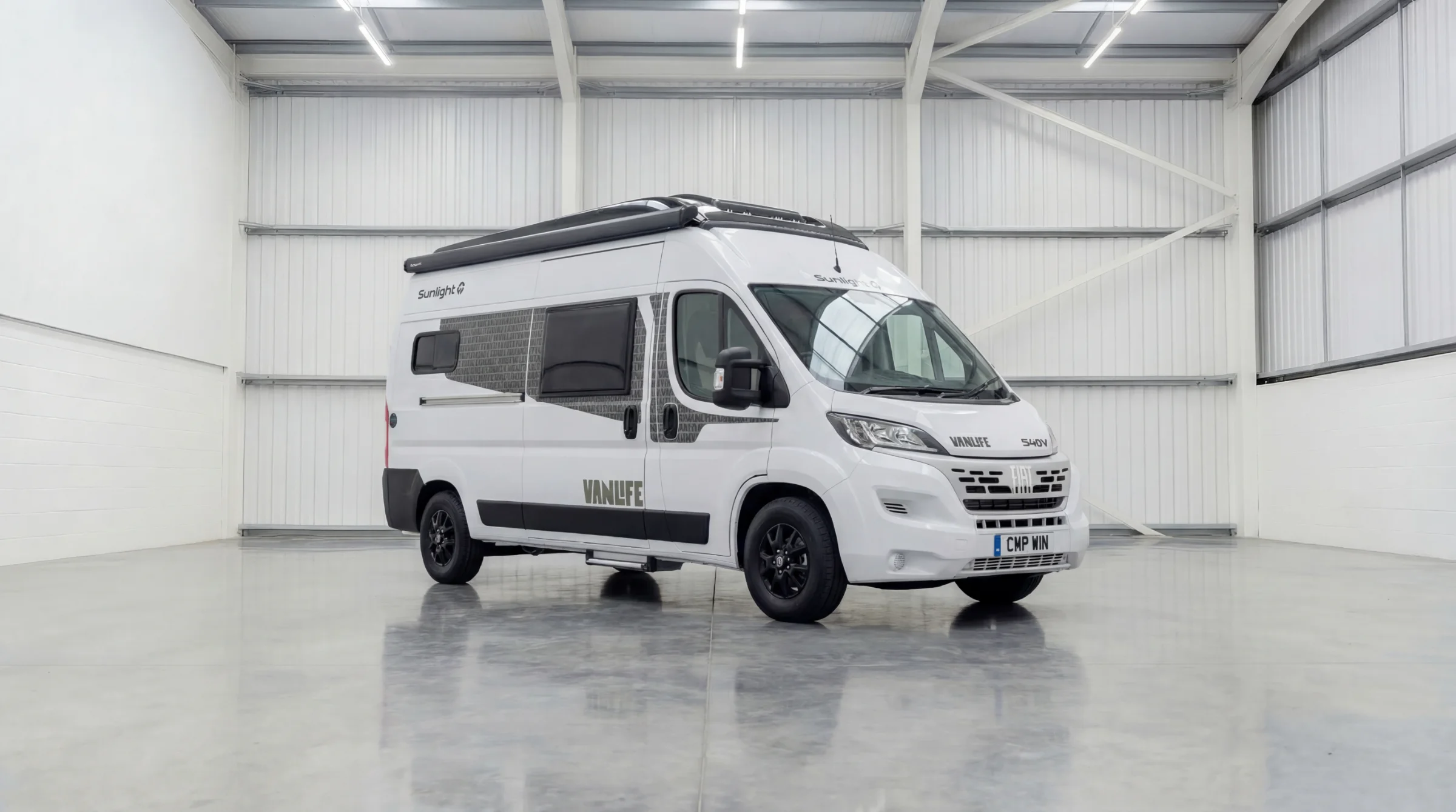 White Sunlight Vanlife campervan with roof rack parked in bright warehouse, front view with CMP WIN number plate.